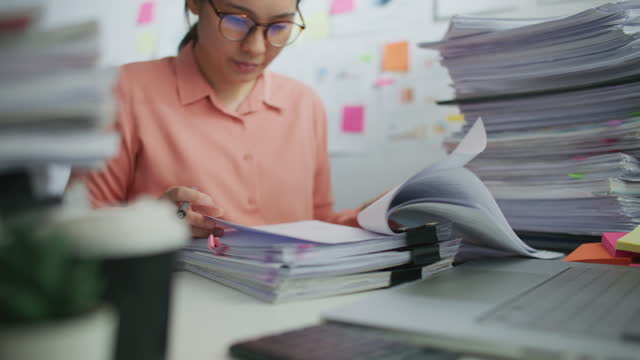 Businesswoman working with stacks of document paper on desk