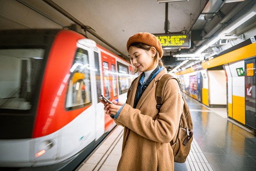 Gen z girl commuting on the subway uses smartphone
