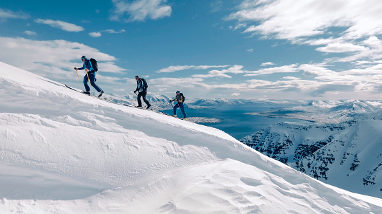 Group of four diverse tourists or hikers are walking on mountain top at sunset time