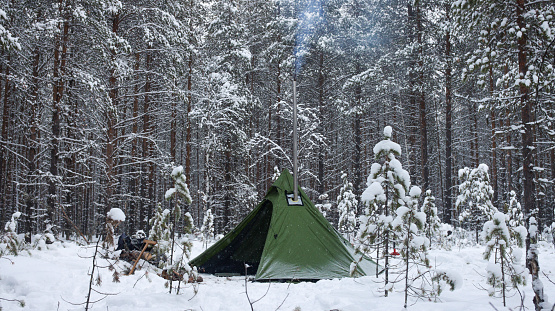 Winter camping with a tent. Tent in winter landscape. Green tent in a beautiful winter forest