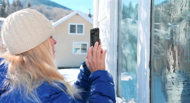 Mature woman photographs ice crystals on window