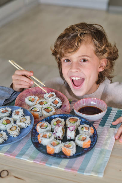 istock Cheerful boy eating sushi in kitchen 2013074836