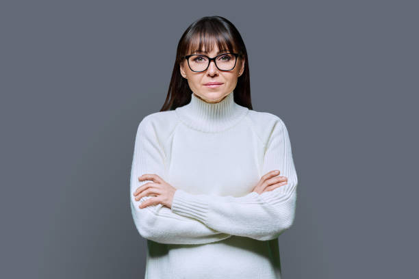 istock Middle-aged beautiful serious woman in white sweater on gray studio background 2013078560