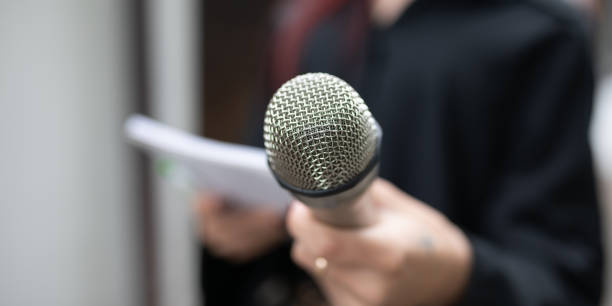 istock Journalist at news conference, writing notes, holding microphones 2013079498