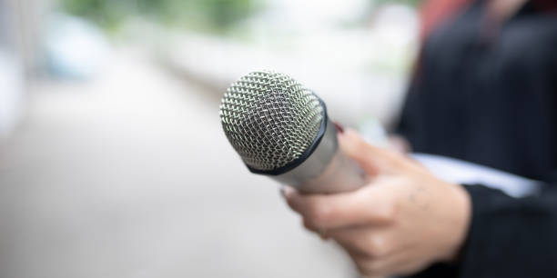 istock Journalist at news conference, writing notes, holding microphones 2013080007