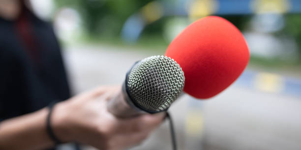 istock Journalist at news conference, writing notes, holding microphones 2013080133