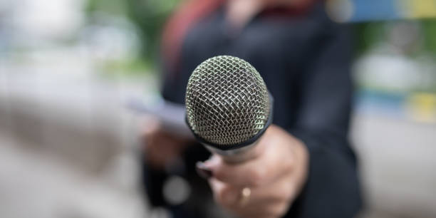 istock Journalist at news conference, writing notes, holding microphones 2013080227