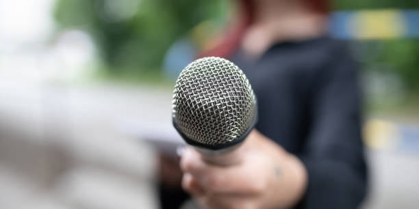 istock Journalist at news conference, writing notes, holding microphones 2013080310