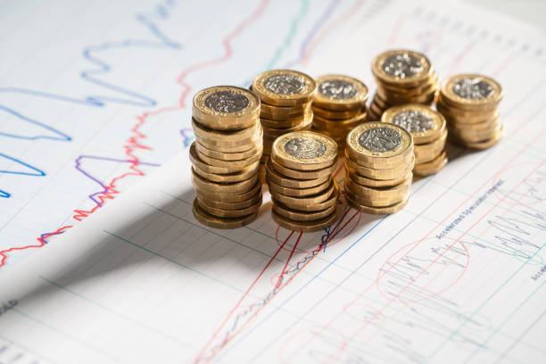 stack of pound coins on financial graphs and figures - verlies fotos stockfoto's en -beelden