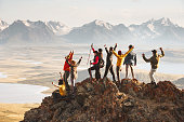 Large group of tourists celebrates the completion of their climb to the top of the mountain.