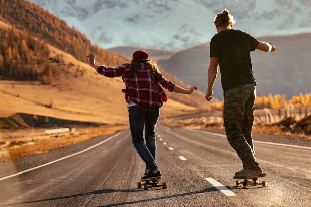 istock Young couple hipsters rides on longboards at sunset mountain road 2013090424