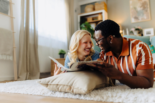 Young couple reading magazines. They are talking and sharing some laughs.