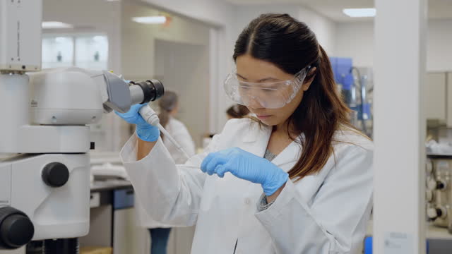 Female scientist drops sample onto microscope slide