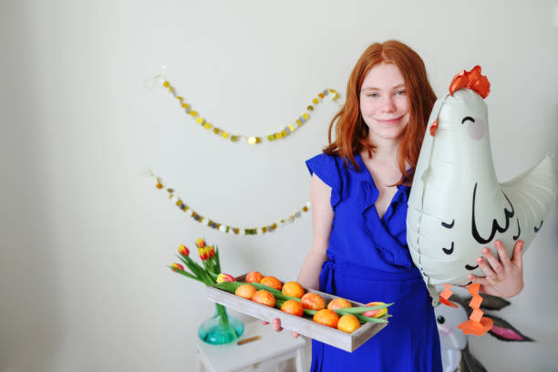 girl with balloons of chickens hold plate with Easter eggs. Easter holiday