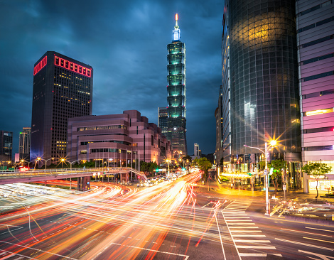 A long exposure blurring busy evening rush hour traffic in Taipei's financial downtown district at dusk.