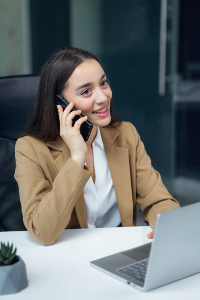 istock Happy woman using mobile phone and laptop for work. Confident business lady working from office. 2013109323