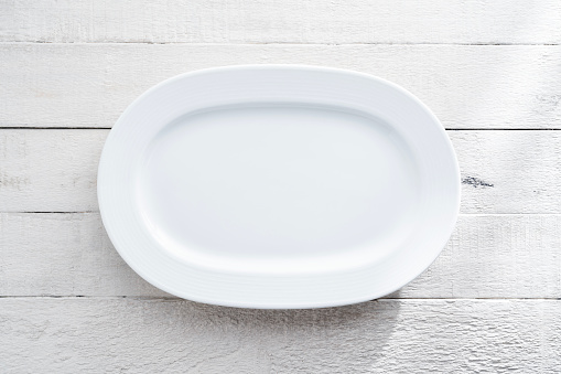 Blank white plate on wood background
