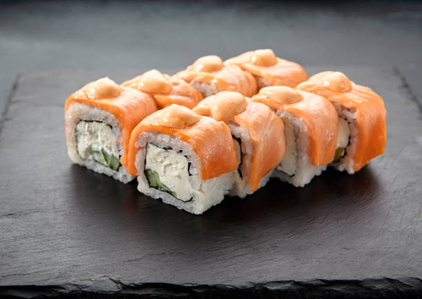 Baked Philadelphia sushi rolls with spicy sauce, offering a creamy and tangy taste in each bite Baked Philadelphia sushi rolls with spicy sauce, offering a creamy and tangy taste in each bite. tangy stock pictures, royalty-free photos & images