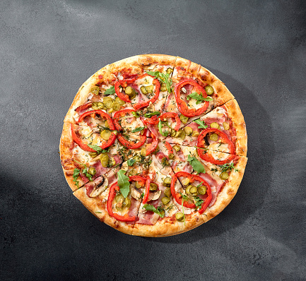 Meat lovers' pizza with bacon, ham, marinated pickles, and paprika, bursting with flavors and toppings.