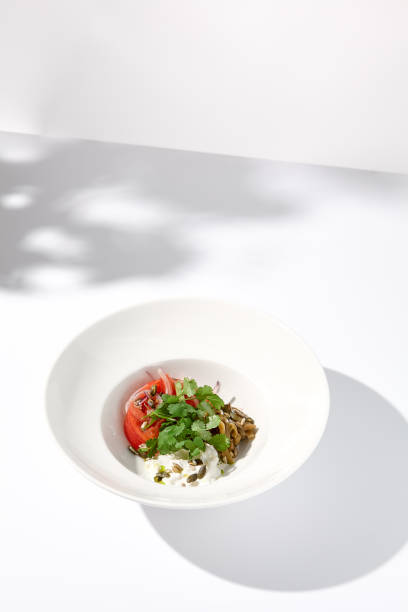 istock Artistic shadow over a salad with tomatoes, stracciatella cheese, and eggplants garnished with cilantro 2013146321