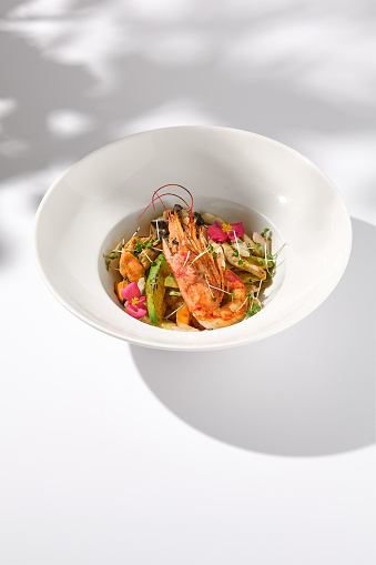 Zucchini Seafood SautÃ© with Shrimp and Elegant Floral Garnish on Shadowed White.