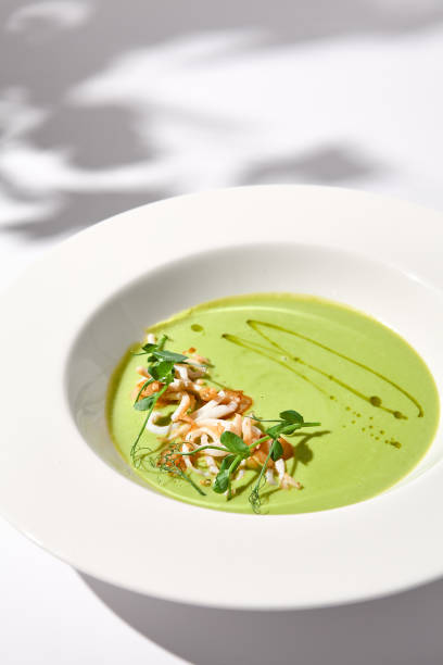 istock Spinach Cream Soup with Calamari Topping, Artfully Presented on a White Plate with Shadow, Perfect for Gourmet Food Advertising 2013146851