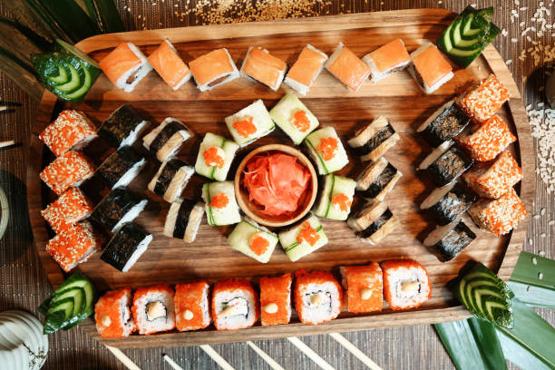 Wooden Tray Topped With Sushi and Vegetables