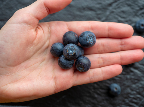 Fresh blueberry on hands. Female hand holding blueberries.