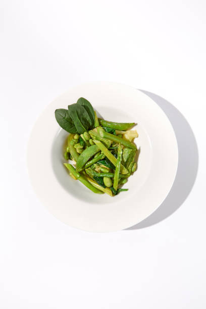 Green vegetable garnish with asparagus, zucchini, and edamame beans isolated on white background, top view