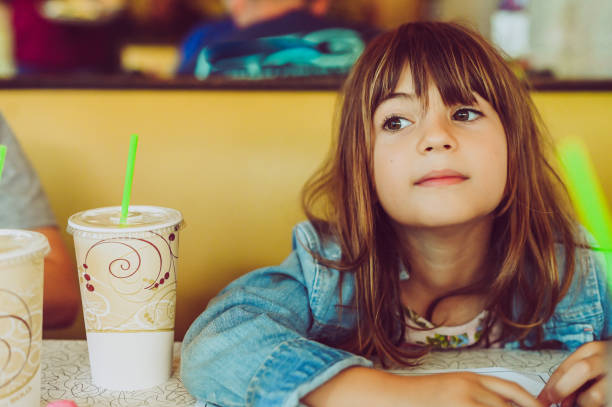 istock Cute candid kid sitting at a restaurant or diner both for fast casual food 2013165486