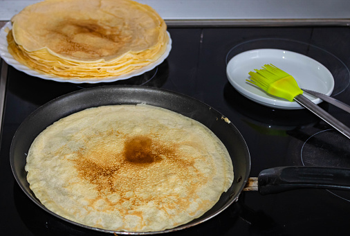 Frying homemade crepes in a pan on the  stove