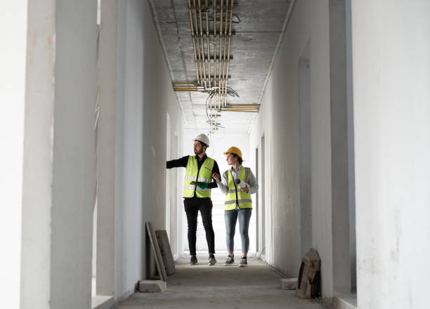 istock Caucasian engineer man and woman working with tablet computer and paper work in building at construction site 2013213279