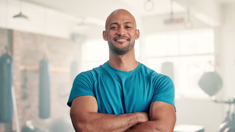 Man, face and arms crossed in gym with smile, pride or training for muscle development. Person, confident and happy for exercise, workout or fitness with health for body transformation at boxing club