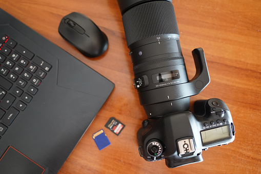 DSLR camera, laptop, SD cards, mouse  on a desk.