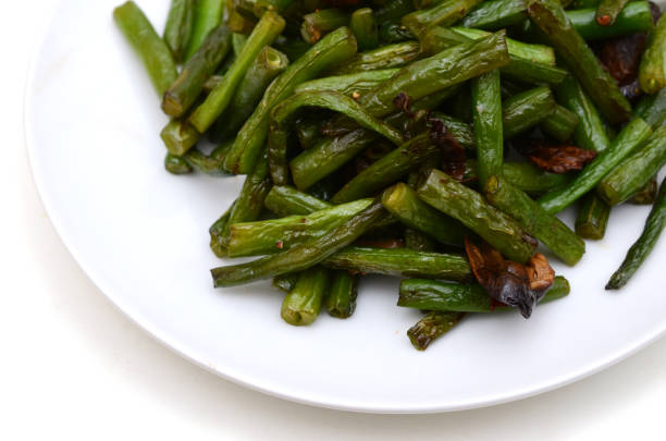 Green beans with garlic carrots on a yellow plate on a purple background.green beans with carrots top view. healthy vegan food.