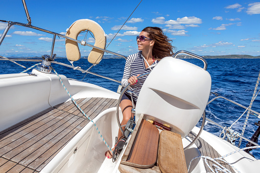 An attractive woman steers a sailboat on the Mediterranean Sea, Croatia