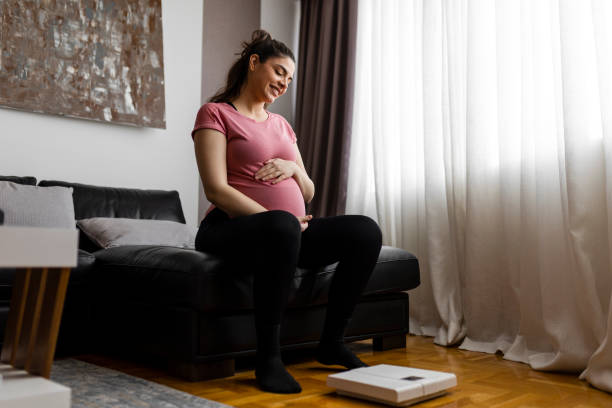 istock Pregnant woman weighing herself on a scale 2013248363