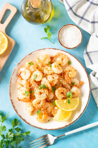 Fried shrimps with herbs and olive oil at blue table.