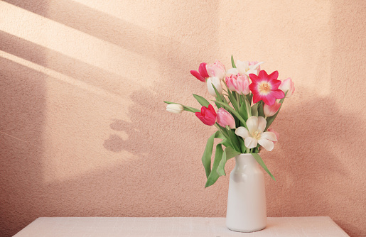 tulips in vase on table on background wall