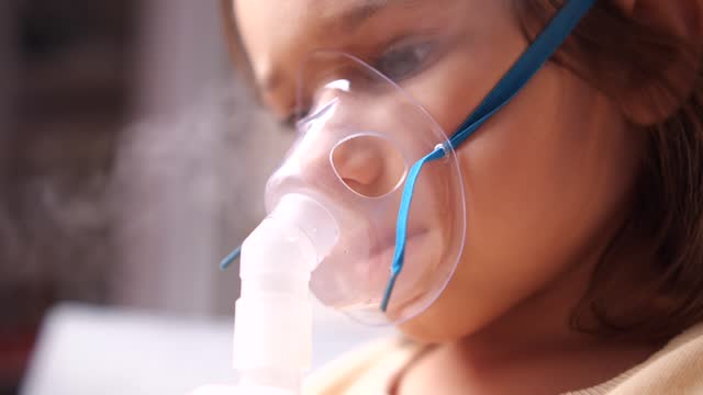 close-up of girl wearing nebulizer mask, inhaler. Girl inhales medication vapor