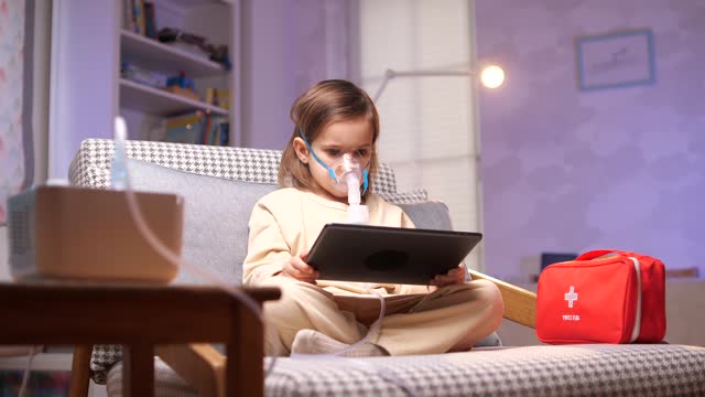 girl watching cartoons on a tablet. medical procedure on nebulizer inhaler