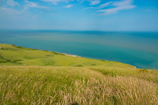 Amazing views from a walk along coastal pathway near seaside town of Eastbourne. Picturesque green hilly coastline of South England above the turquoise blue sea. Exploring around scenic English coast.