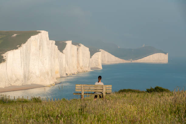 istock Female traveller sits on wooden bench and admires breathtaking white cliffs 2013309428