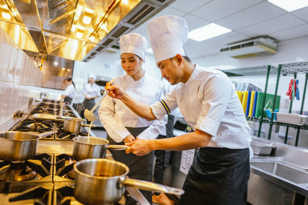 istock Guided Culinary Mastery: Asian Female Adult Students Excel under Professional Cooking School Instructors - Professional Cooking School 2013318034