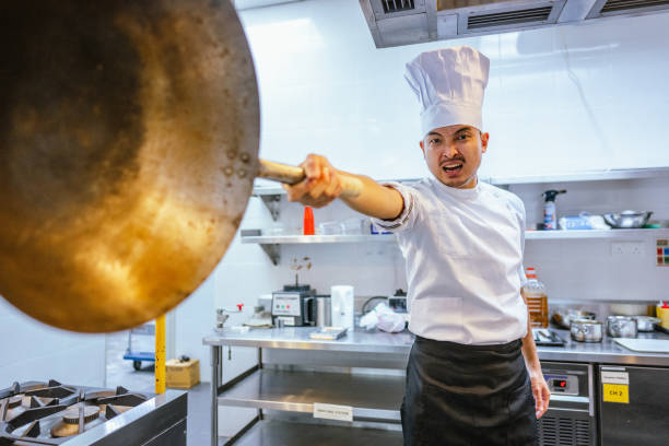 ปลุกเร้าความสําเร็จ: จิตวิญญาณที่มุ่งมั่นของเชฟชาวเอเชียในการฝึกอบรม ภาพสต็อก