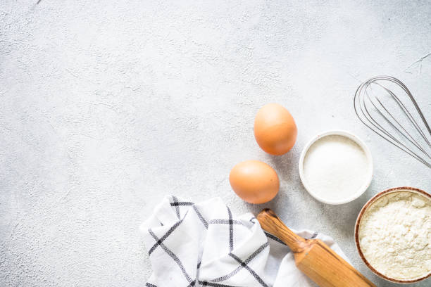 istock Baking background ingredients. Flour, sugar, eggs and rolling pin at light stone table. 2013326588