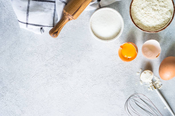 istock Baking background ingredients. Flour, sugar, eggs and rolling pin at light stone table. 2013327109