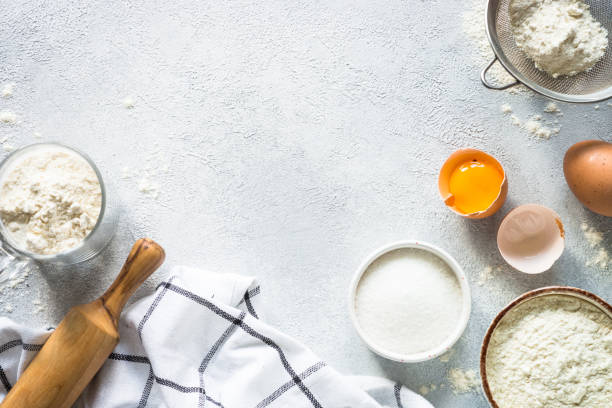 istock Baking background ingredients. Flour, sugar, eggs and rolling pin at light stone table. 2013327114