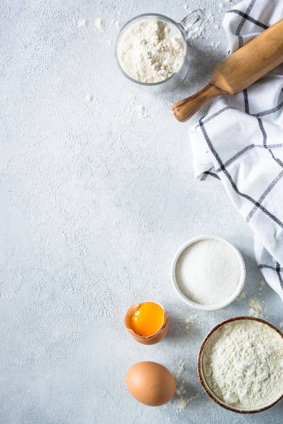 istock Baking background ingredients. Flour, sugar, eggs and rolling pin at light stone table. 2013327117
