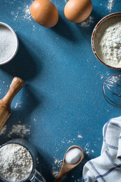 istock Baking background ingredients. Flour, sugar, eggs and rolling pin at blue stone table. 2013328195